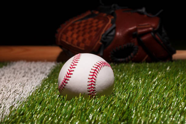 istock Baseball on grass field low angle close up with mitt and bat soft focus behind 1400885590