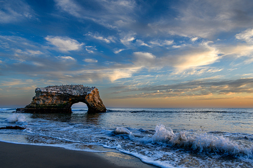 Sunset view of the Natural Bridges mudstone formation that is carved by the Pacific Ocean into cliffs that jutted out into the sea.\n\nTaken in Santa Cruz, California, USA