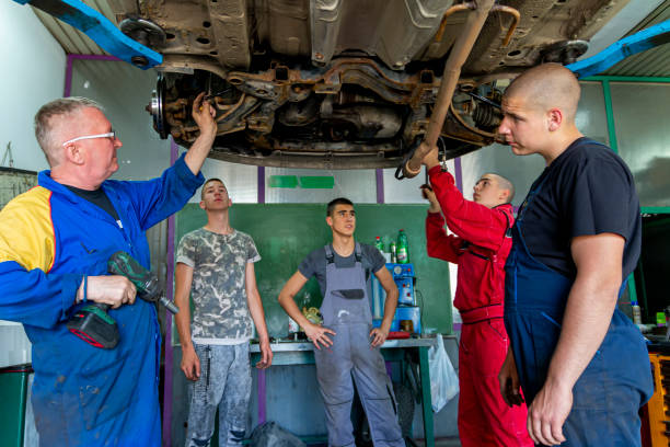 istock Male tutor with students on auto mechanic apprenticeship course at college 1400907168