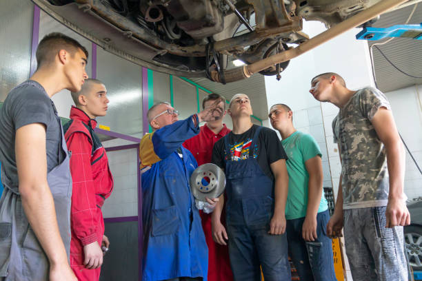 istock Male tutor with students on auto mechanic apprenticeship course at college 1400907207