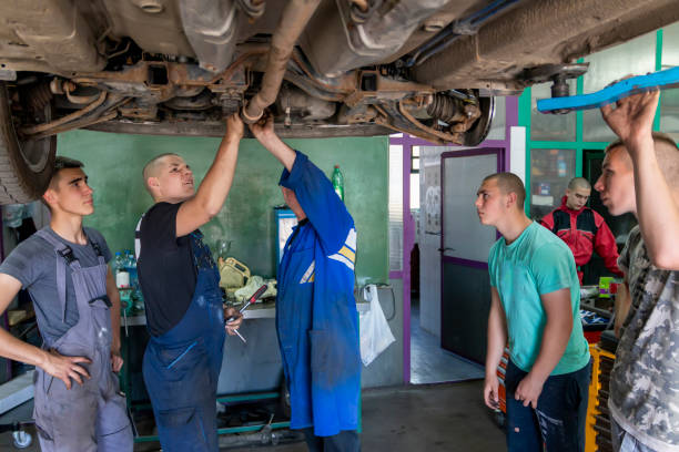 istock Male tutor with students on auto mechanic apprenticeship course at college 1400907344