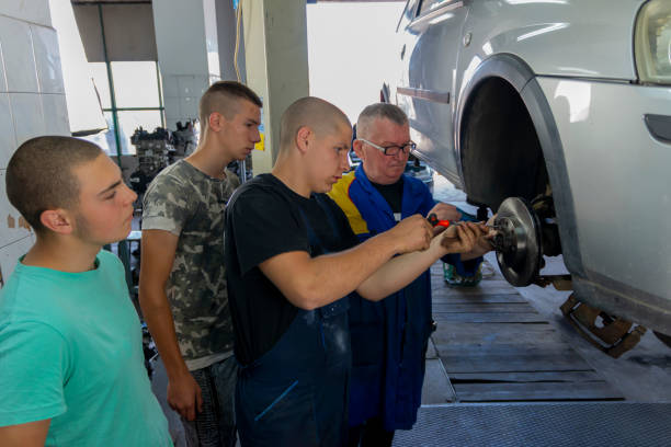 Male tutor with students on auto mechanic apprenticeship course at college