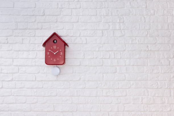 reloj de pájaro cuco con péndulo rojo en una pared de ladrillo blanco - reloj cuco fotografías e imágenes de stock