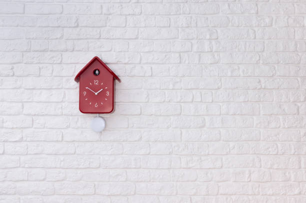 白いレンガの壁に赤い振り子を持つカッコウ鳥時計 - pendulum photography color image nobody ストックフォトと画像