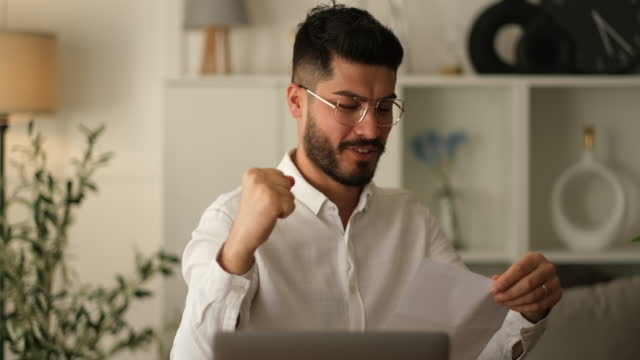 Excited male worker entrepreneur opening mail letter reading good news