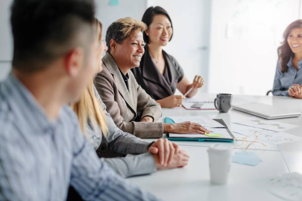 une femme mûre multiraciale assiste à une réunion avec un groupe multiracial de collègues dans un intérieur de bureau créatif - presentation business adult student seminar photos et images de collection