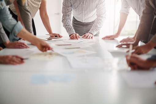 Vista de ángulo bajo de las manos de un grupo multirracial de personas que trabajan con ideas y hacen una lluvia de ideas juntas para tomar decisiones con documentos sobre la mesa en el trabajo en equipo creativo de la oficina photo