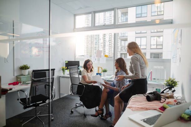 istock Small group of women sitting within creative office interior discussing plans and ideas with document in hand 1400929215