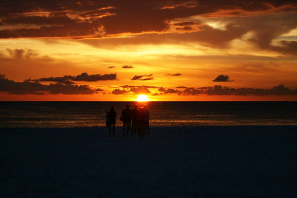 istock Small Group of People on Beach Watching Sunset in Silhouette with Dramatic Sky 1400929312
