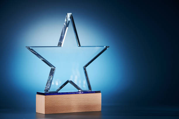 trofeo en forma de estrella de cristal sobre fondo azul - ganar fotografías e imágenes de stock