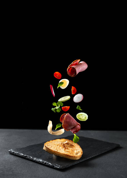 istock A sandwich on a black background. The ingredients fly in the air. Empty space for text. Sandwich with vetchina and vegetables 1400933080