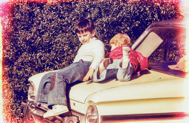Vintage photo of two children sitting and playing on top of an auto. Vintage photo o the seventies of the 20th century.