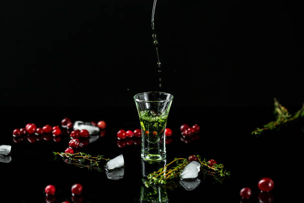 freeze motion shot absinthe poured into a glass. bottle of absinthe with cranberries and lime isolated on black background. space for text freeze motion shot absinthe poured into a glass. bottle of absinthe with cranberries and lime isolated on black background. space for text. absinthe spoon stock pictures, royalty-free photos & images