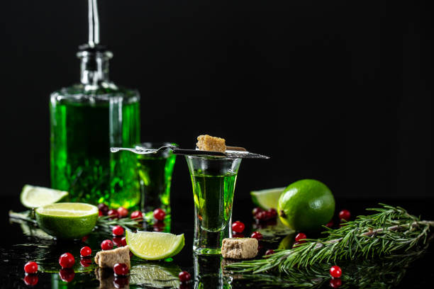 traditional set for drinking absinthe. alcohol, luxurious spirits and dangerous liquor absinthe, pouring on stainless steel spoon, brown sugar, cranberries and lime, green bottle of strong spirit - lime imagens e fotografias de stock