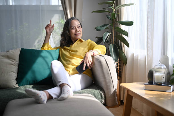 istock Attractive mature woman resting on comfortable sofa and looking through the window. 1400941562