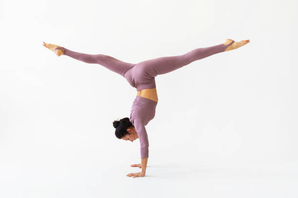 istock A woman practicing yoga performs the Adho Mukha Vrikshasana exercise with Samakonasana, handstand with longitudinal splits on a white background 1400942525