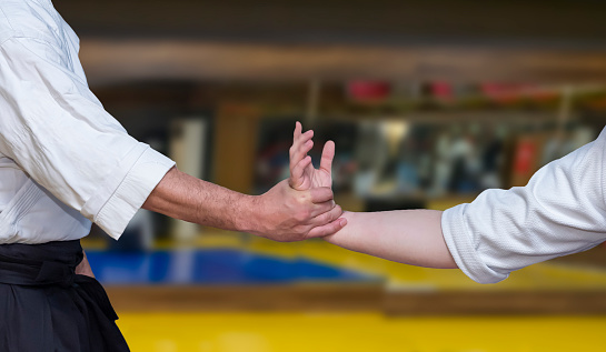 Aikidoka uses the technique joint lockon the opponent during the training of aikido, close up