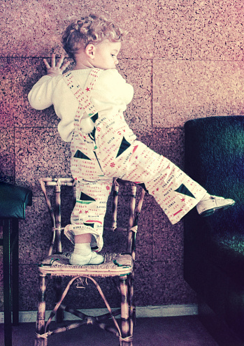 Vintage photo featuring a child playing at home on top of a chair. Vintage photo of the seventies of the 20th century.