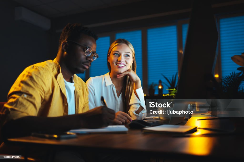 Two business people working with laptop overtime at night Happy couple celebrating the success of paying bills while sitting at home at night. Business Stock Photo