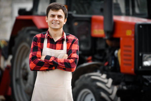 istock young man farmer looking to the camera with his tractor in a background. 1400952704