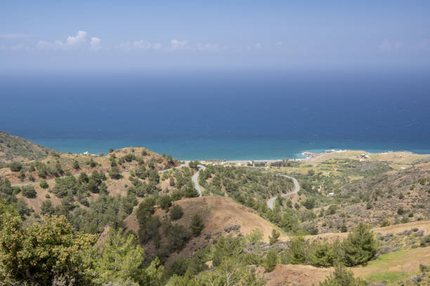 istock Road winding down sparsely vegetated volcanic hillside to seaside village 1400954392
