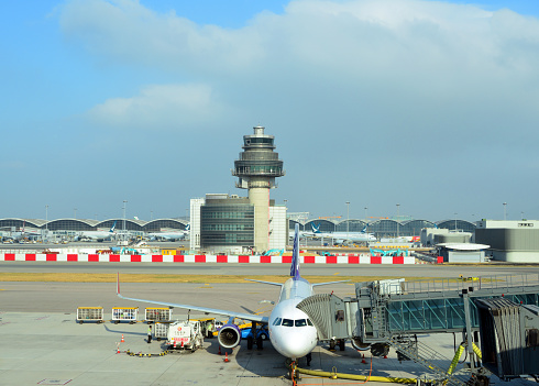 Hong Kong, China: Air Traffic Control Complex (ATCX), control tower and support building - Hong Kong International Airport (HKIA) - Chek Lap Kok island. View from the Midfield Concourse with an HK Express Airbus A320 aircraft at a PBB, with Terminal 1 in the background.