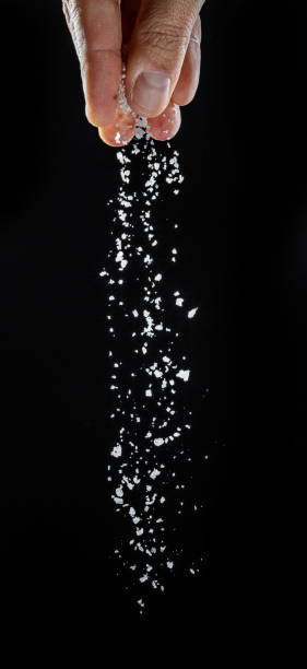 istock Male hand sprinkling edible salt at black background. 1400957273