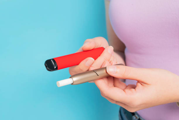 sigaretta elettronica usa e getta e iqos in mano da vicino. - tobacco sticks foto e immagini stock