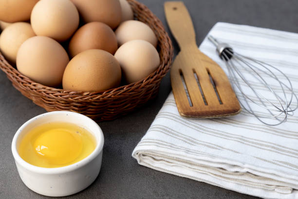 istock Free-range chicken eggs in a wicker basket. Broken egg, egg yolk. A wooden spatula, and a whisk. 1400959145
