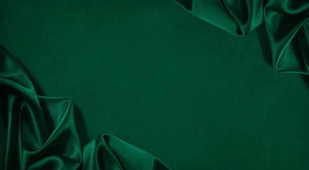 dark green silk satin background. beautiful soft folds on the smooth surface of the fabric. luxury background - green silk textile shiny imagens e fotografias de stock