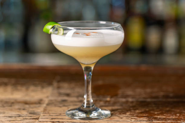 Pisco Sour cocktail on the bar. Blurred background. Pisco Sour cocktail on the bar. Blurred background. Peruvian, Mexican, Chilean traditional drink pisco sour liqueur with lime and egg. liquor store counter photos stock pictures, royalty-free photos & images