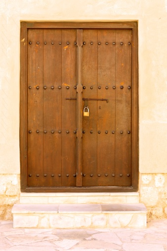 A door of an old house in the Bastakiya area of Dubai, in the United Arab Emirates. Many of the houses are well over 100 years old and have been built along typical Gulf Arabian traditions. Photo shot in the morning sunlight; vertical format.  No people.