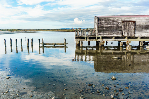 Old timber wharf and shed on lagoon in small town of Okarito, Westland, New Zealand.