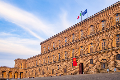 Tourists resting at sunset in front of Palazzo Pitti, a Renaissance palace in Florence, that now represents the largest museum complex of the city