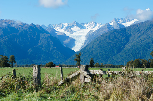 Fox Glacier viewed over rustic farm gate from rural road.