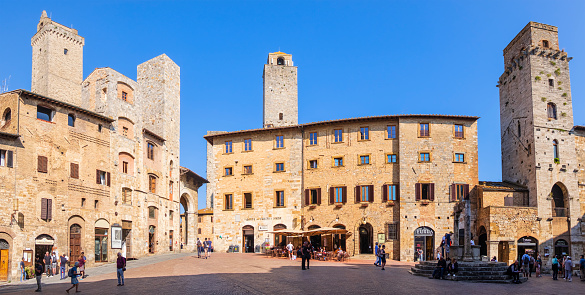 Tourists strolling in Piazza della Cisterna in San Gimignano, a small walled medieval town whose historic centre has been declared a UNESCO World Heritage Site