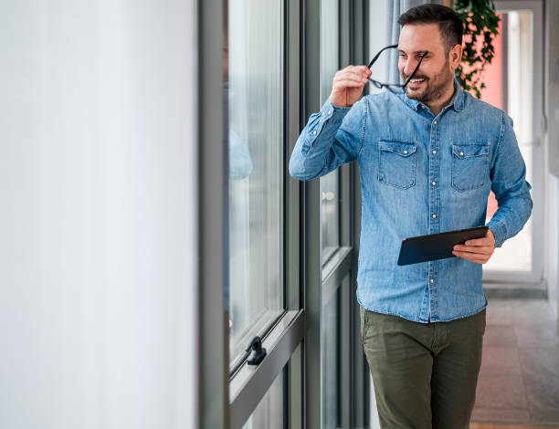 istock Businessman with digital tablet wearing eyeglasses while looking through window 1400967201