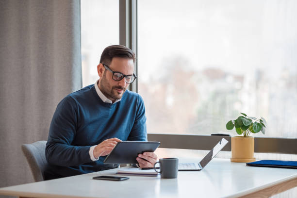 istock Businessman using digital tablet while working on laptop at office desk 1400967269