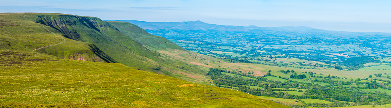 The steep escarpment of the Black Mountains overlooking the Brecon Beacons and the patchwork rural landscape of fields and pasture of Wales, UK.