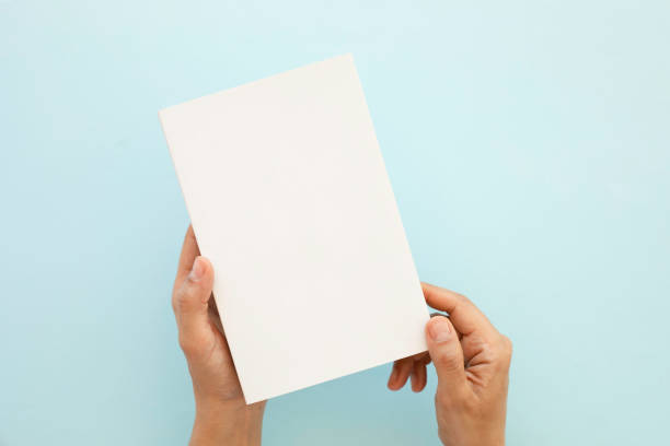 青い背景に空白の本を持っている男の切り取られた手 - brochure blank paper book cover ストックフォトと画像
