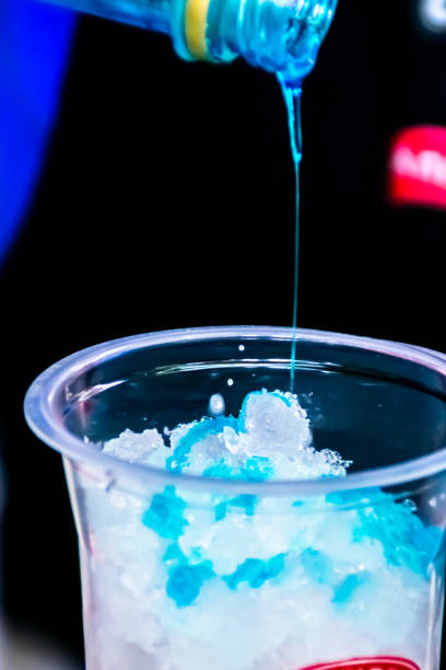 istock Pouring a sweet blue syrup into a transparent plastic glass with cold shaved ice inside with a blurry and soft focused background 1400971948