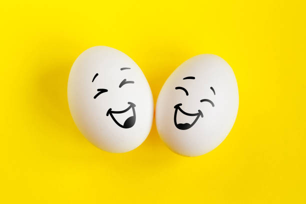 due uova bianche sul concetto di sfondo giallo. emozioni risate e felicità. amicizia, concetto di relazione. - funny eggs foto e immagini stock