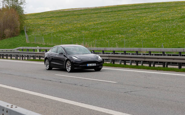Black German electric Tesla 3 driving on the A7 Autobahn Kempten, Allgäu, Schwaben, Bavaria, Germany, may 1st 2022, a black German electric Tesla model 3 from the Ulm district approaching on the German A7 Autobahn at Kempten - with a length of 963 km between the borders of Denmark in the north and Austria in the south, the Autobahn 7 is the longest Autobahn in Germany - the majority of the German Autobahn does not have a mandatory but only an advisory speed limit tesla model 3 stock pictures, royalty-free photos & images