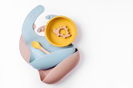 Juego de vajilla infantil y baberos de silicona. Accesorios para bebés. Concepto de nutrición y alimentación. Vista superior, plano lay photo
