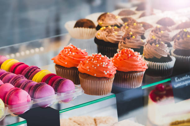 istock Showcase with sweets in the cafe. Cupcakes and colored macaroons on the cake display. Sweet desserts 1400974570