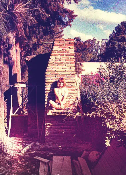 Vintage image of a woman sitting outdoors in a summer house under construction. Vintage image from the seventies.