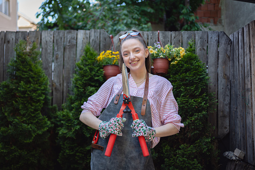 Portrait of young Caucasian female florist in her garden with pruning shears