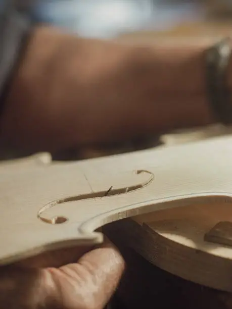 violinmaker cutting and sawing cremonese violin model fholes with a blade with precision