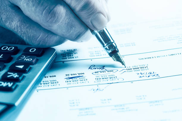 Man uses a fine old fountain pen to amend figures on a printed spreadsheet.