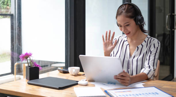 istock Happy asian woman young wearing headset, communicating with client via video computer call. 1400980169